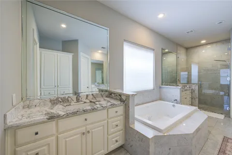 a bathroom with a sink double vanity granite tub shower and a mirror