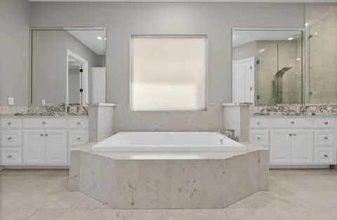 a spacious bathroom with bathtub sink and mirror