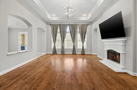 a view of an empty room with wooden floor fireplace and a window