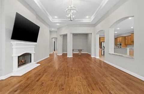 a view of a livingroom with a fireplace a chandelier and wooden floor