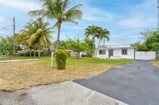 a view of a house with a yard and palm trees