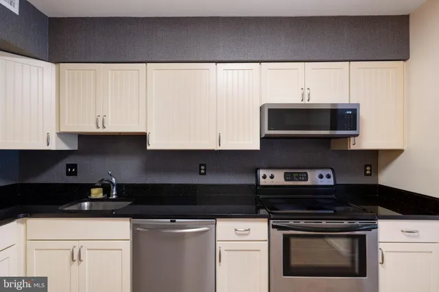 a kitchen with granite countertop white cabinets and black appliances