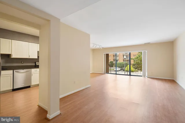 a view of an empty room with a window and wooden floor