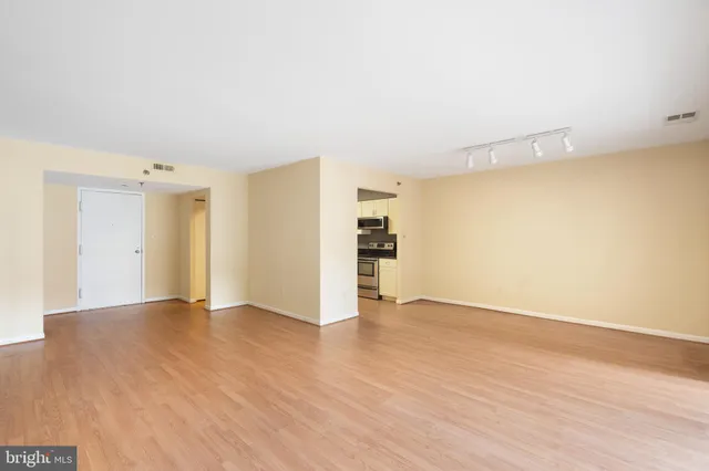 a view of an empty room with wooden floor and closet
