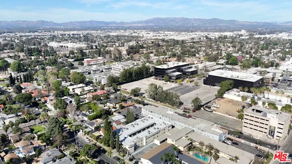 an aerial view of a city with lots of residential buildings and mountain view in back