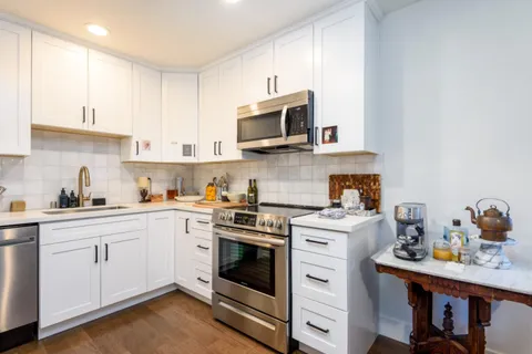 a kitchen with stainless steel appliances granite countertop a sink a stove and microwave with wooden floor