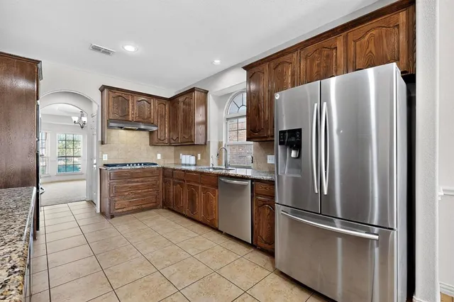 a kitchen with granite countertop cabinets a sink stainless steel appliances and cabinets