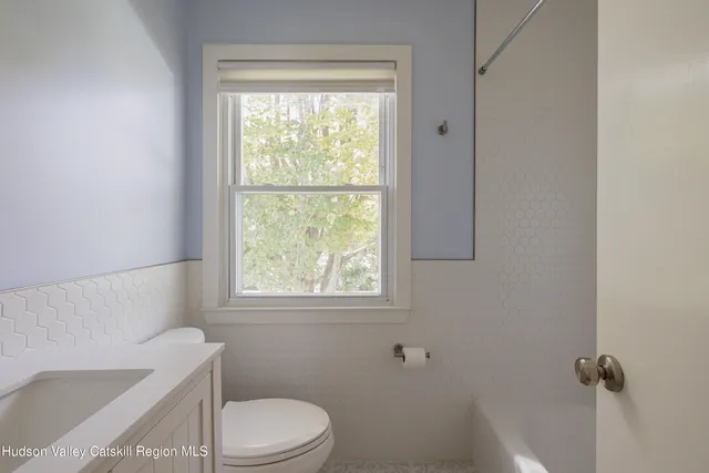 a white toilet sitting next to a window in a bathroom