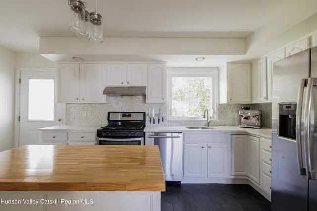 a kitchen with stainless steel appliances granite countertop a stove a sink and white cabinets