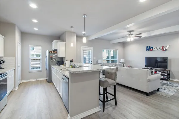 a kitchen with stainless steel appliances granite countertop a sink dishwasher stove top oven and refrigerator with wooden floor