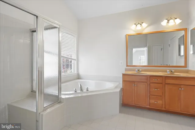 a bathroom with a tub a sink and a large mirror