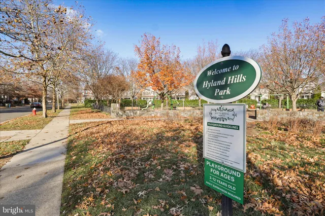 a sign board with tall trees in the background