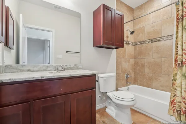 a bathroom with a granite countertop toilet sink and mirror