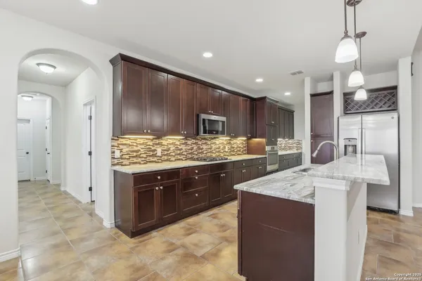 a kitchen with stainless steel appliances kitchen island granite countertop a sink and a refrigerator