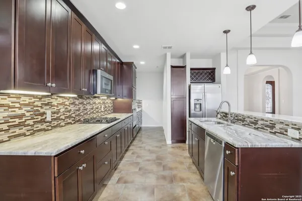 a kitchen with kitchen island granite countertop a sink and a refrigerator