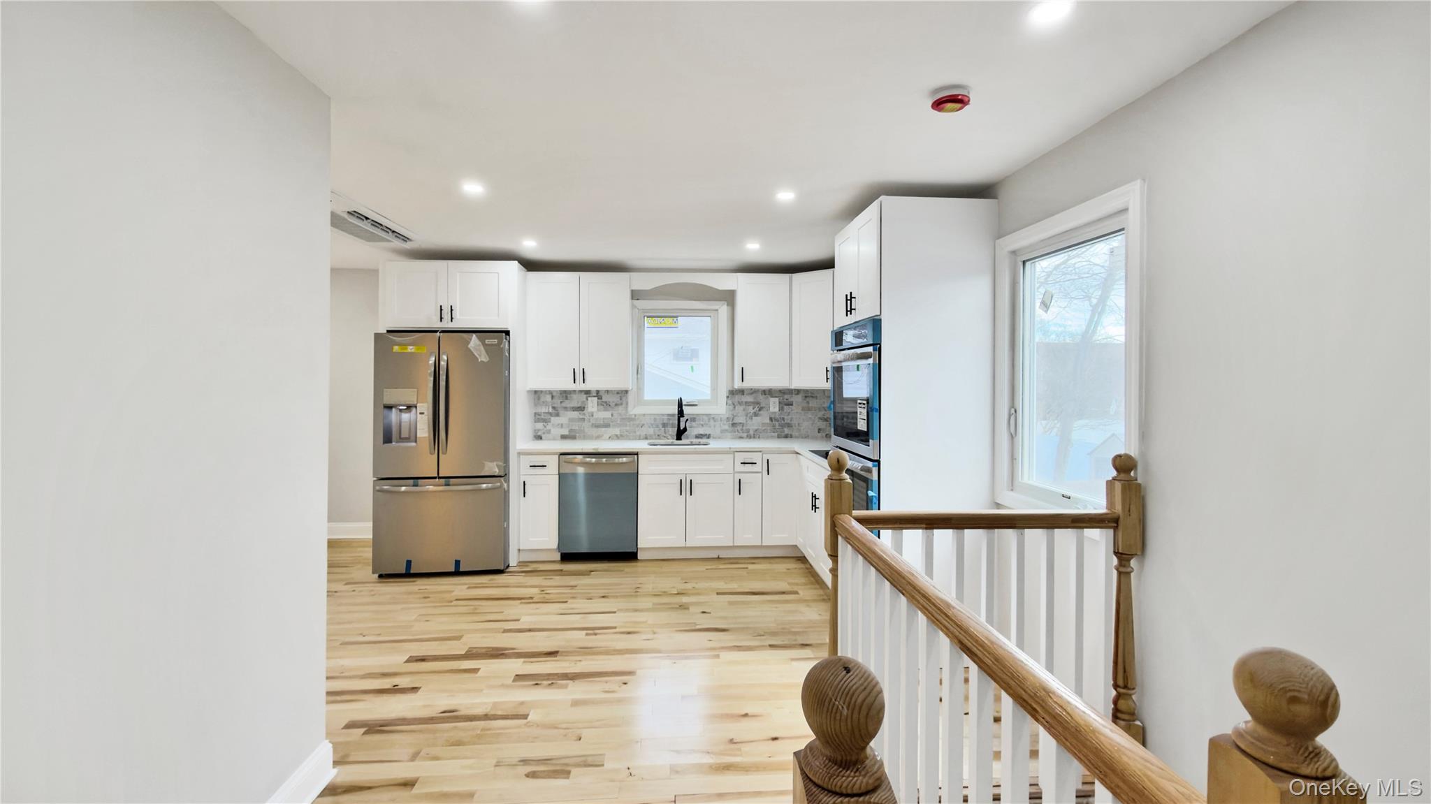 37 Deal Road Island Park, NY 11558 - Photo 19 of 50 Kitchen featuring white cabinets, appliances with stainless steel finishes, light countertops, light wood-style flooring, and recessed lighting