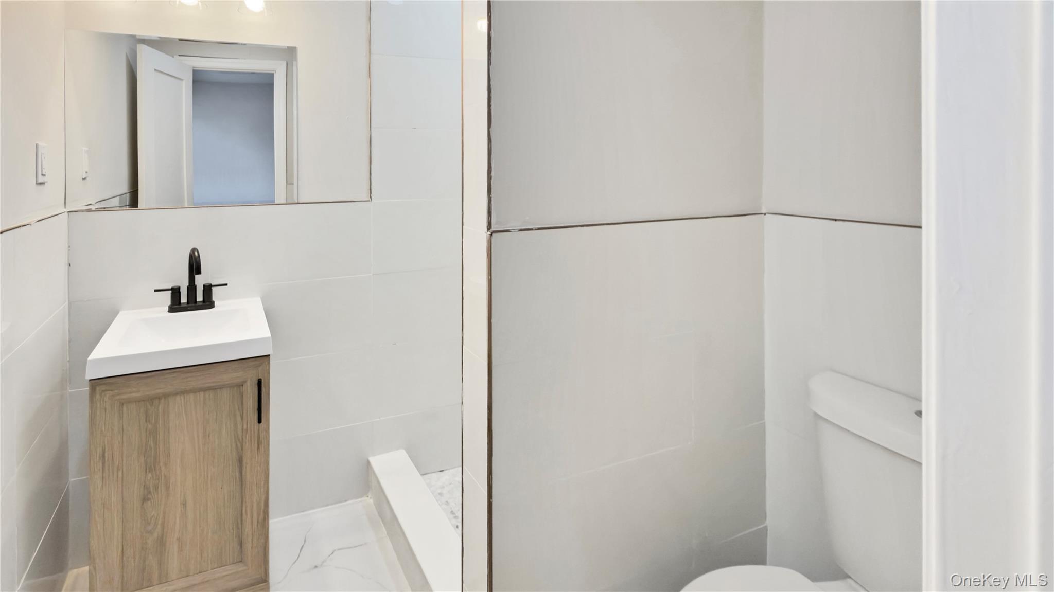 37 Deal Road Island Park, NY 11558 - Photo 30 of 50 Full bath with vanity, tile walls, light marble finish floors, and a shower stall