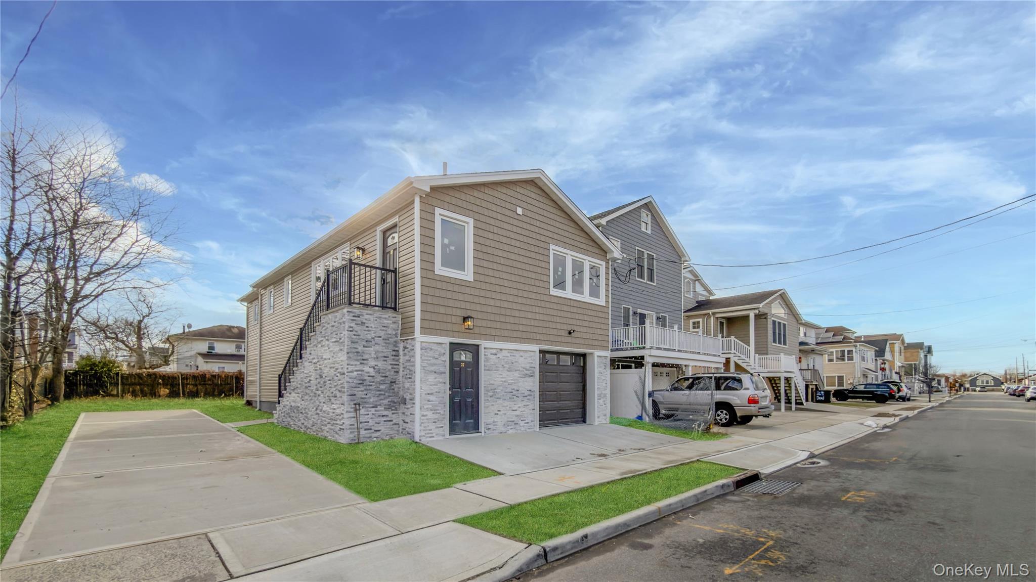 37 Deal Road Island Park, NY 11558 - Photo 3 of 50 View of home's exterior with a residential view, brick siding, driveway, a balcony, and stairway