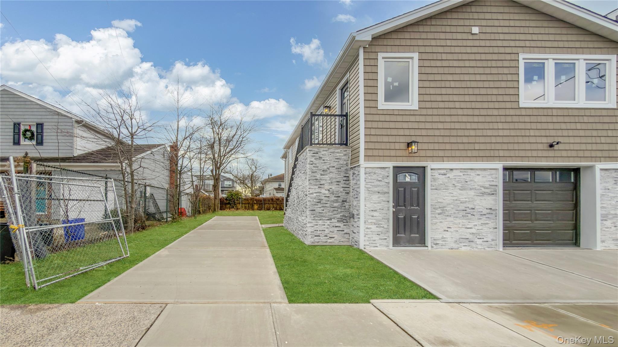37 Deal Road Island Park, NY 11558 - Photo 6 of 50 View of home's exterior with brick siding, a balcony, and concrete driveway