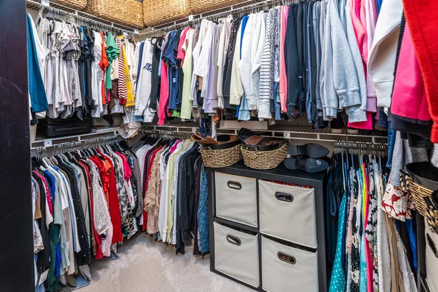 a view of walk in closet with clothes and shoes