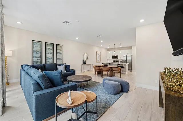 a living room with furniture a flat screen tv and kitchen view