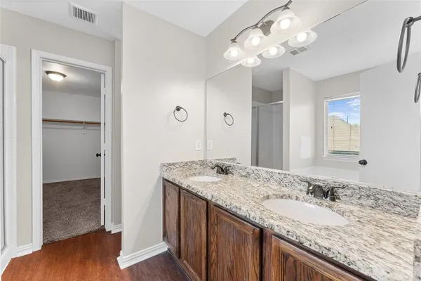a bathroom with a granite countertop double vanity sink and a mirror