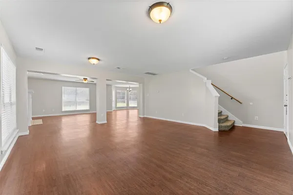 a view of an empty room with wooden floor and stairs