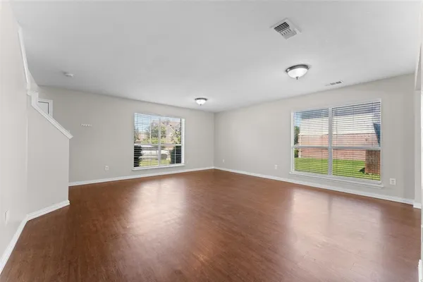 an empty room with wooden floor and window