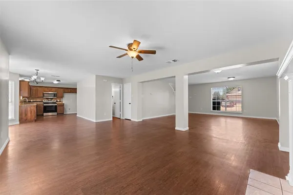 a view of an empty room with a kitchen and wooden floor