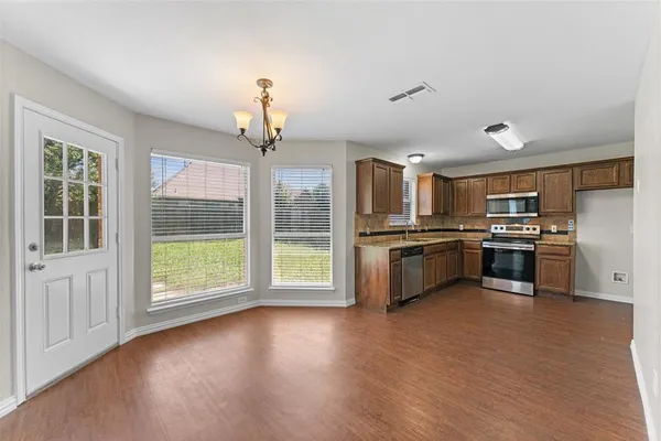 a large kitchen with stainless steel appliances a large counter top a sink and a window