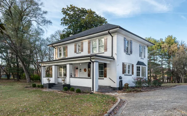 a view of a white house with large windows next to a yard