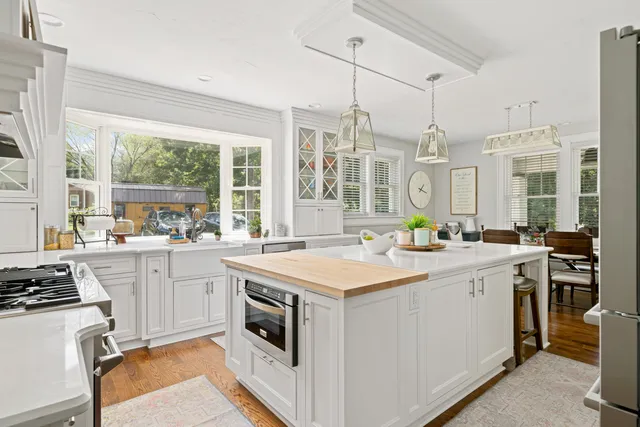 a kitchen that has a lot of white cabinets and stainless steel appliances