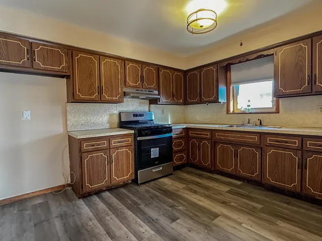 a kitchen with stainless steel appliances granite countertop a stove a sink dishwasher and a microwave with wooden cabinets