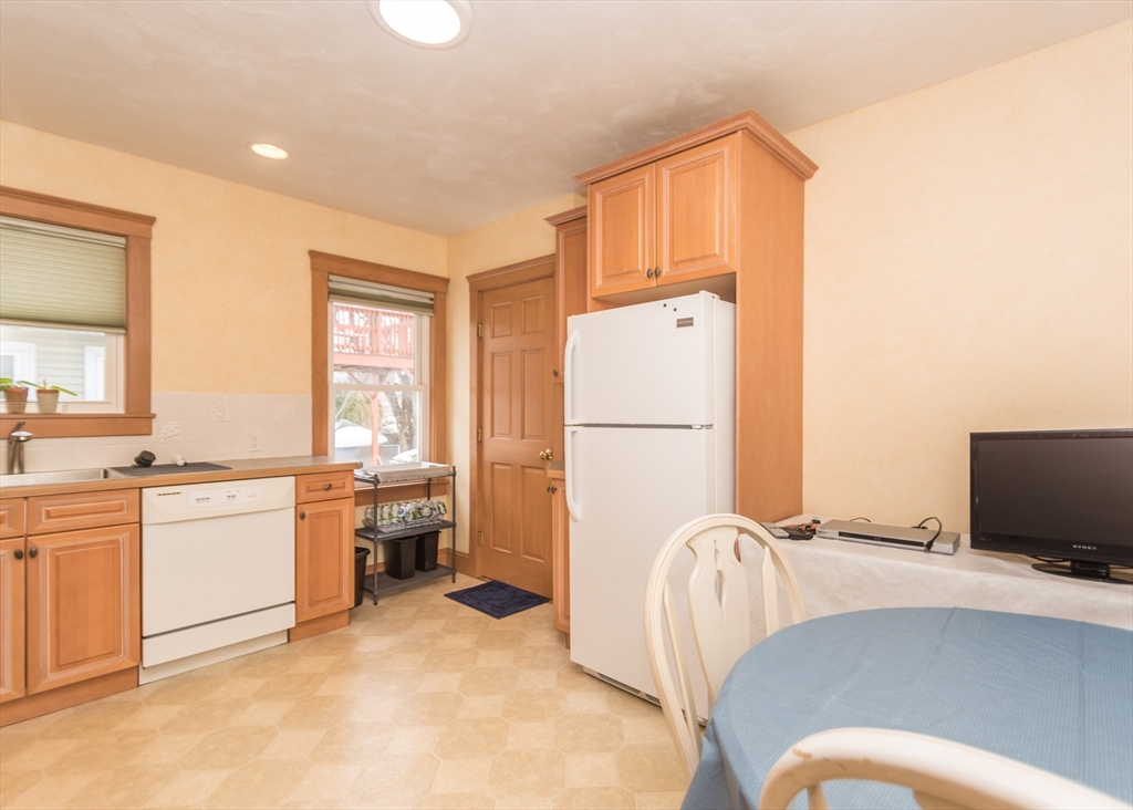 279-281 Ash Street Waltham, MA 02453 - Photo 25 of 39 a living room with furniture a flat screen tv and a refrigerator