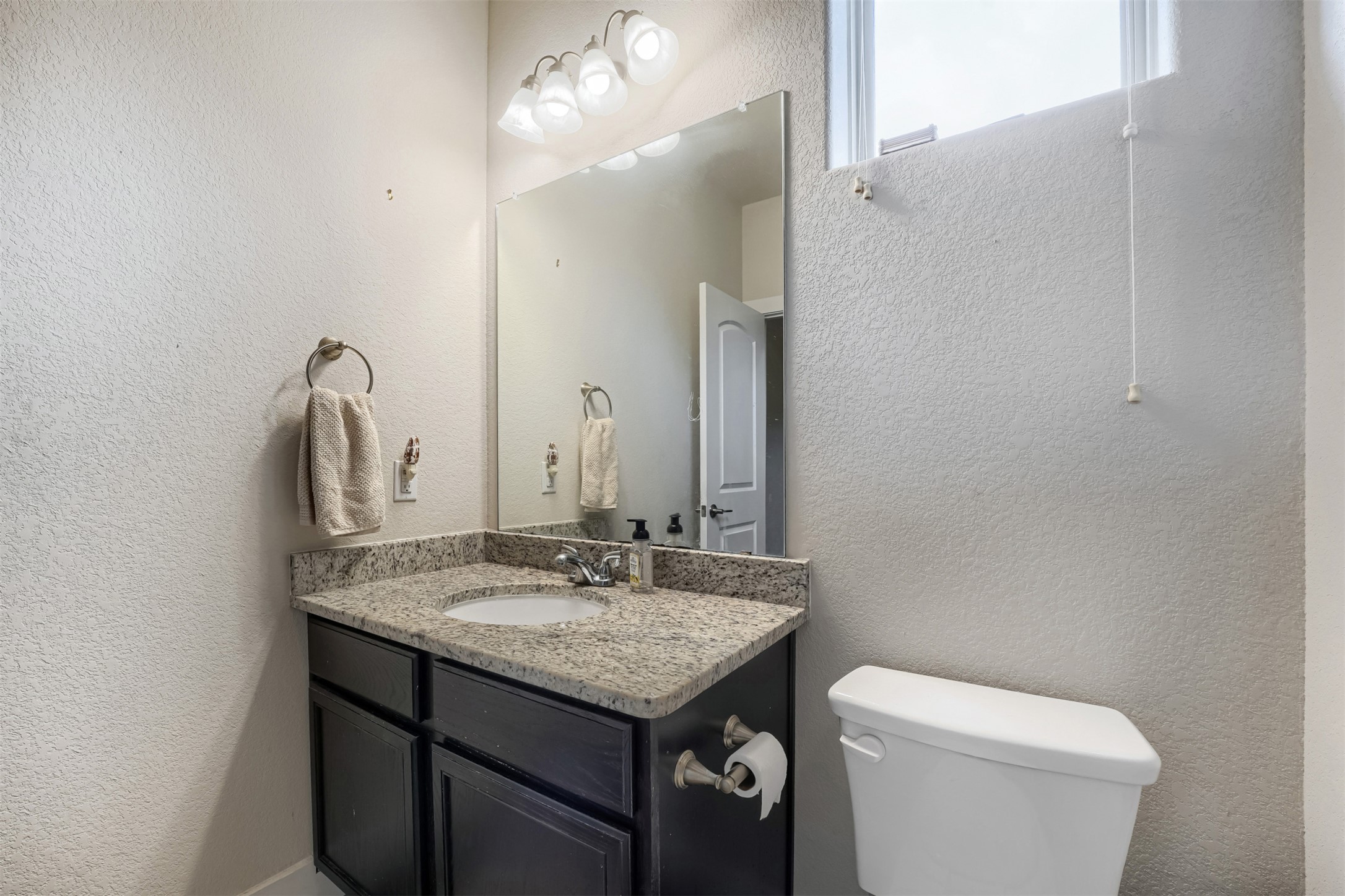 418 High Tech Drive Georgetown, TX 78626 - Photo 20 of 34 Vanity featuring a light granite countertop with an undermount sink, dark wood-finish cabinetry, and a chrome faucet