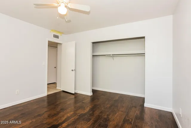 an empty room with wooden floor and a ceiling fan