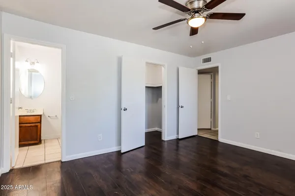 an empty room with wooden floor and a ceiling fan