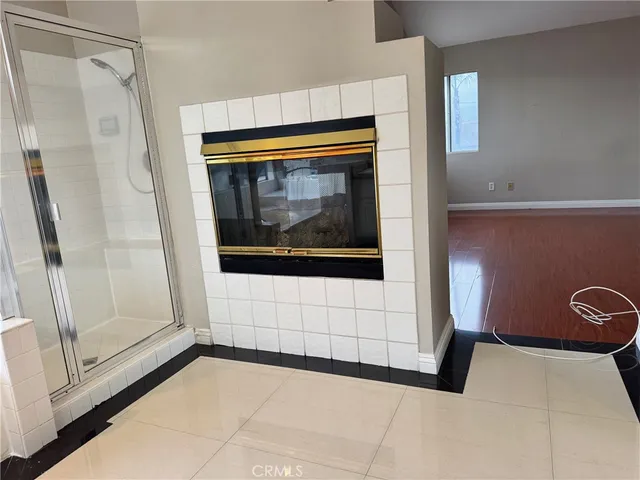 a view of an empty room with wooden floor and a fireplace