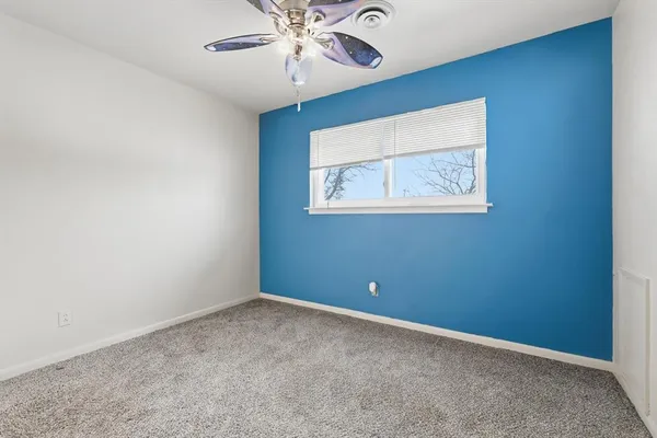an empty room with a window and a fan