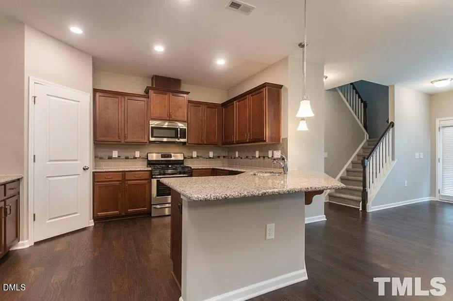 1142 Lookout Ridge Road Apex, NC 27502 - Photo 3 of 21 a kitchen with stainless steel appliances granite countertop a refrigerator a stove a sink dishwasher and a refrigerator with wooden floor