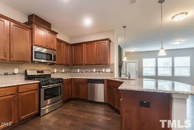 a large kitchen with granite countertop a sink dishwasher stove and cabinets