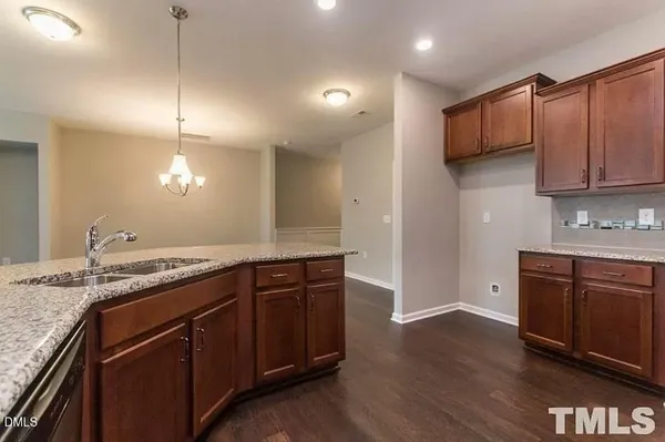 a kitchen with granite countertop a sink cabinets and wooden floor