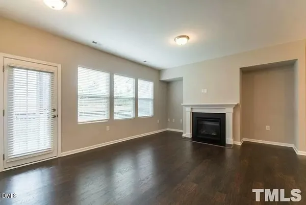 an empty room with wooden floor fireplace and windows