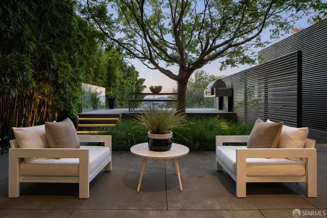 a view of a patio with table and chairs potted plants and large tree