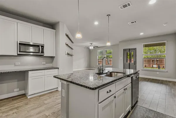a kitchen with granite countertop stainless steel appliances a sink stove and cabinets