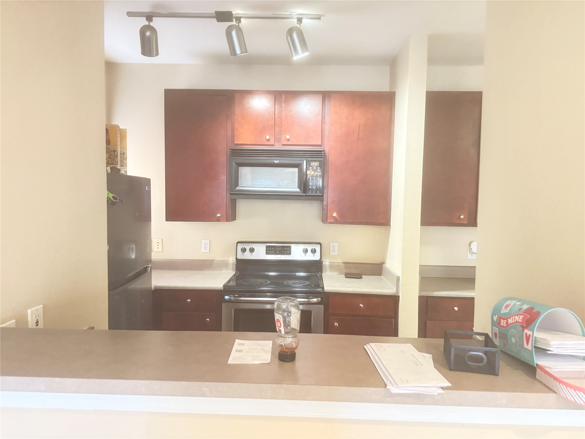 1901 Crossing Place, Unit 1201A Austin, TX 78741 - Photo 4 of 13 Kitchen featuring stainless steel appliances, light countertops, rail lighting, and bold wood finish cabinets