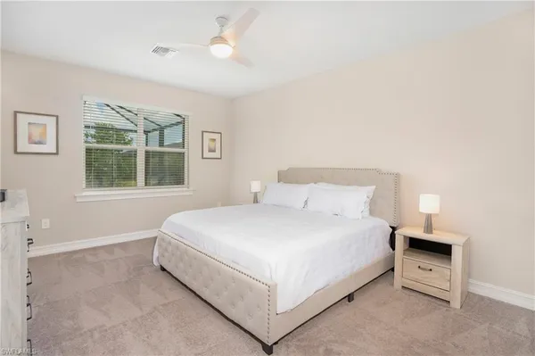 a large bed sitting in a bedroom next to a window and a chandelier