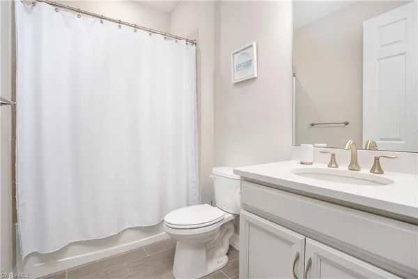 a bathroom with a granite countertop sink toilet and a mirror