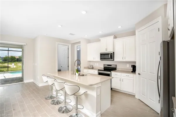 a kitchen with stainless steel appliances a sink a stove a refrigerator cabinets and dining table