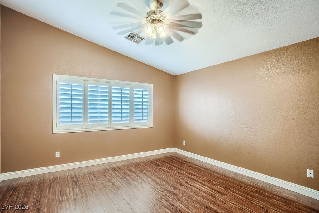 591 Fox Chase Street Henderson, NV 89015 - Photo 10 of 22 Unfurnished room with vaulted ceiling, a textured wall, wood finished floors, and a ceiling fan